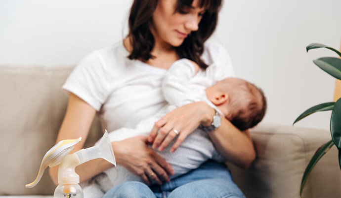 baby and mom breastfeeding on a couch in a well lit room