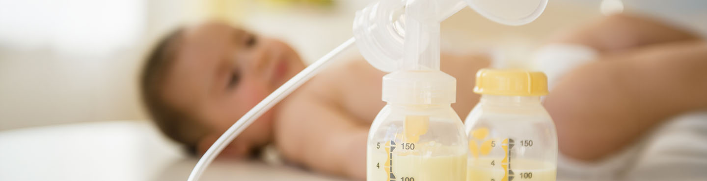 A baby and breastmilk bottles with milk in them beside the baby.